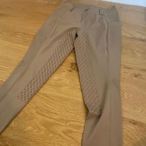 Tan riding tights with belt loops.
